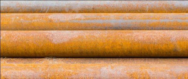 Rostiga stålrör staplade, behov av korrosionsskydd för offshore och industri.