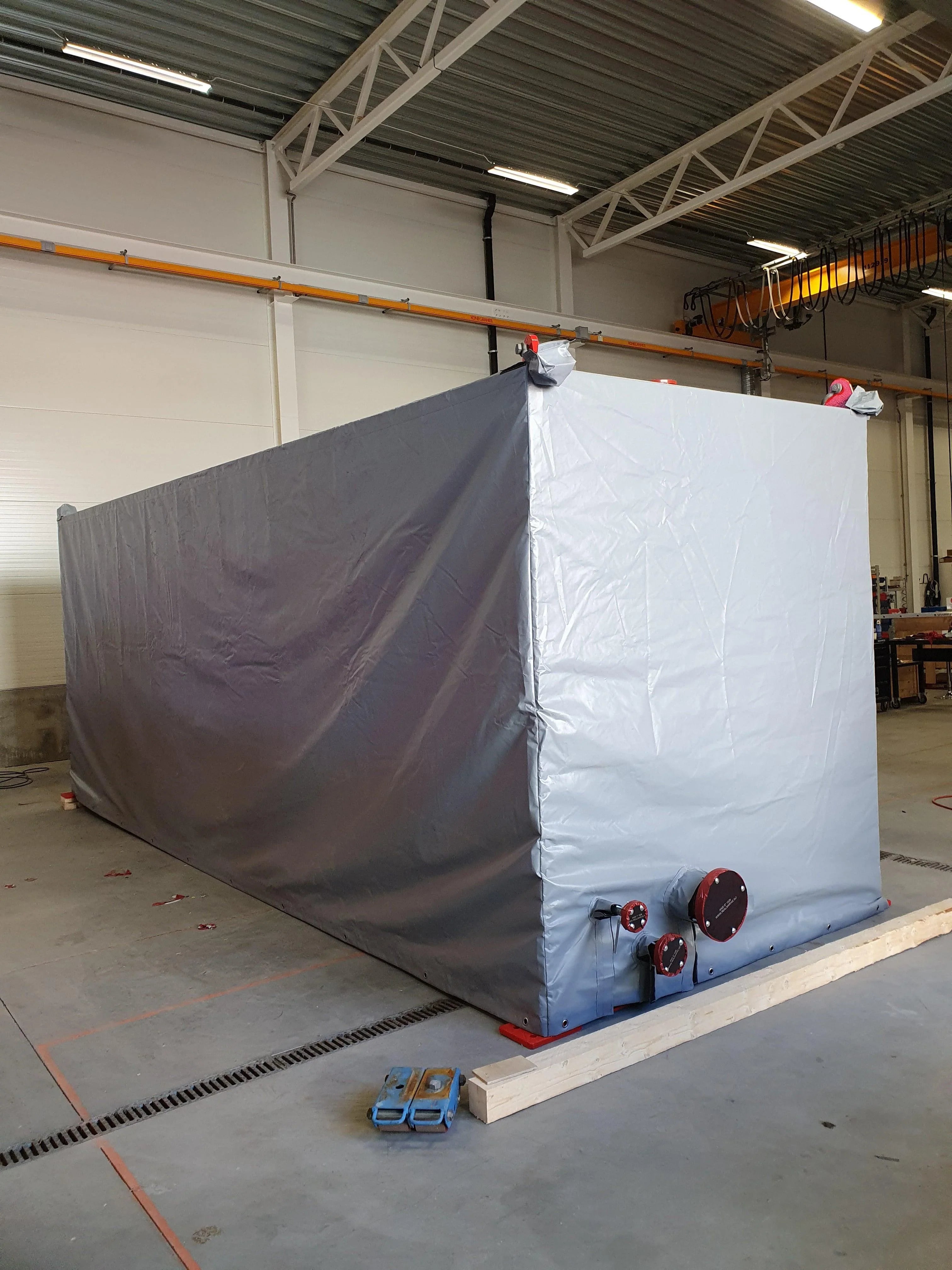 Stor grå presenning som beskytter industrielt utstyr på lager